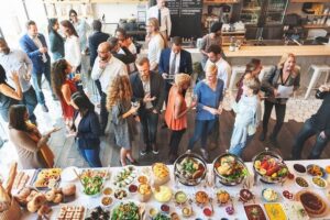 A buffet table with people standing around and talking